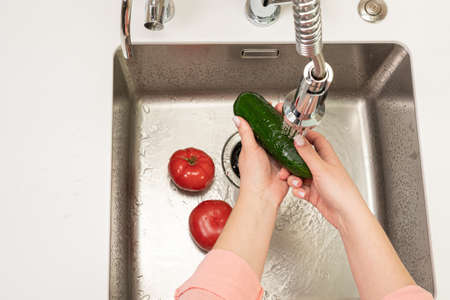 white woman washing vegetables in the kitchen over the sinkの写真素材