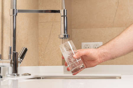 filling a glass with clean, clear drinking waterの写真素材