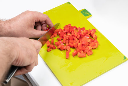 knife cuts bell pepper into a salad on a cutting boardの写真素材