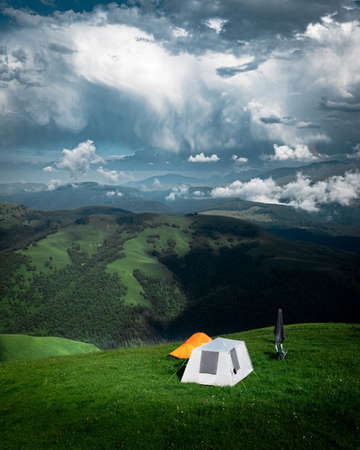 Camping in the mountains with tent standing on a hill, night and sunset landscapeの写真素材