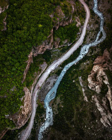 Top view of mountain road in forest with blue riverの写真素材