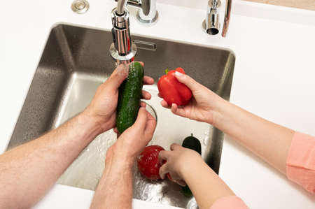 a married couple washes vegetables in the kitchen for lunchの写真素材
