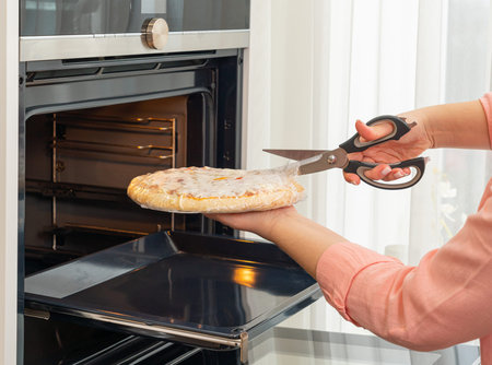 Opening a pizza package before baking in the ovenの写真素材