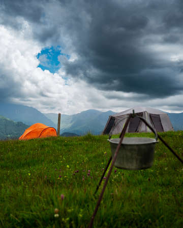 Camping in the mountains with tent standing on a hill, night and sunset landscapeの写真素材