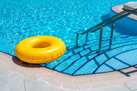 Yellow ring floating in refreshing blue swimming poolの写真素材