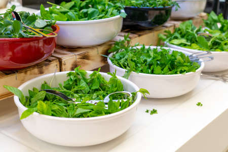 Bowls with fresh greens in hotel buffet. Concept of healthy and diet eatingの写真素材