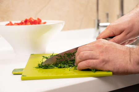 finely chopped dill for salad preparation with a kitchen knifeの写真素材