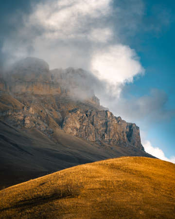 High mountain cliff with low clouds in Caucasus region in Russiaの写真素材