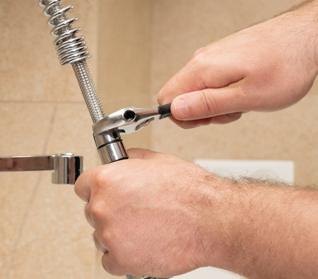 Repair with an adjustable wrench of a modern faucet in the kitchen in the sinkの写真素材