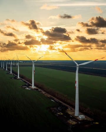 Windmill farm at sunset with dramatic sky. Producing alernative energy. Renewable energy concept.の写真素材