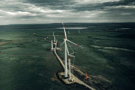 Wind turbine constraction at sunset. Installation the rotor blades on wind turbineの写真素材