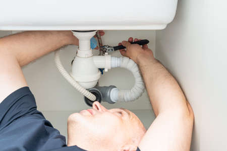 do-it-yourself sink siphon repair by a white adult maleの写真素材