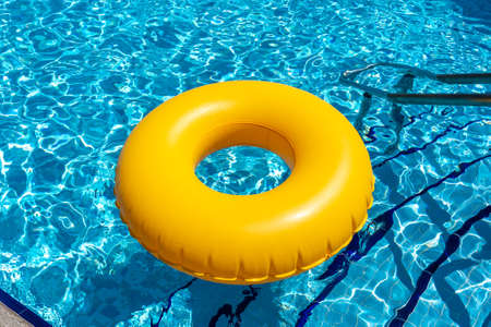 Yellow ring floating in blue swimming pool. Inflatable ring, rest conceptの写真素材