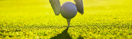 Closeup of golfer wearing glove placing golf ball on a tee at golf courseの写真素材