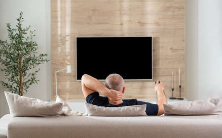 man sitting on sofa in modern living room back viewの写真素材