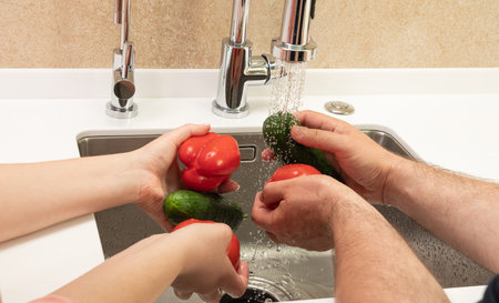 the process of washing vegetables for lunch in the kitchen in the sink.の写真素材