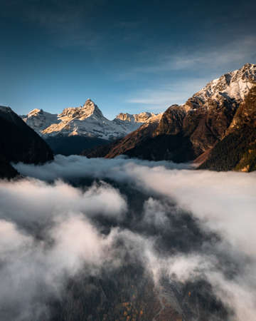 fog in the valley between the mountains overlooking the beautiful skyの写真素材