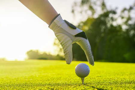 Golfer wearing glove placing golf ball on a tee at golf courseの写真素材