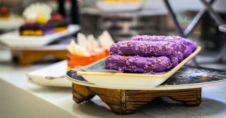 Eclairs with sweet purple topping with nuts on serving plateの写真素材