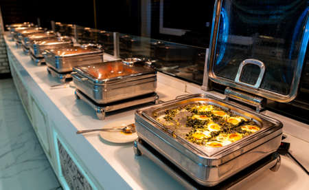 All-inclusive buffet food in heating trays in hotel restaurant with eggs with spinach for breakfastの写真素材