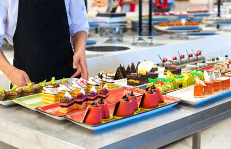 Waiter decorating pastries and cakes in the hotel barの写真素材