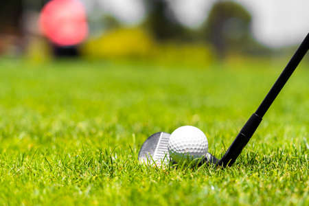 Golf ball and golf club on green grass on golf courseの写真素材