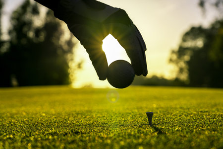 Golfer wearing glove placing golf ball on a tee at golf courseの写真素材