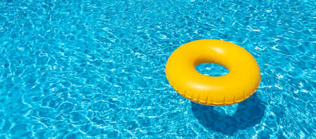 Yellow inflatable ring floating in swimming pool. Vacation concept with copy spaceの写真素材