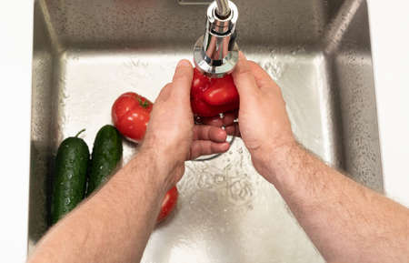 close-up of a man washing vegetables in the kitchen over the sinkの写真素材