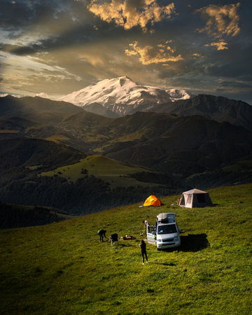Camping in the mountains with tent standing on a hill, night and sunset landscape with helipad for droneの写真素材