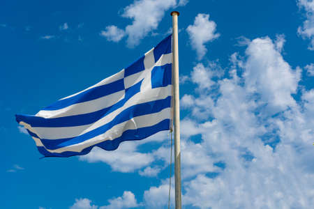 National flag of Greece waving in the wind against a sky with cloudsの写真素材