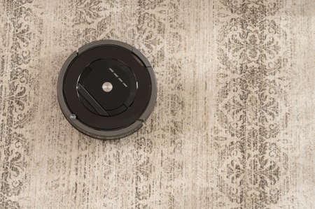 robot vacuum cleaner on carpet top view black colorの写真素材