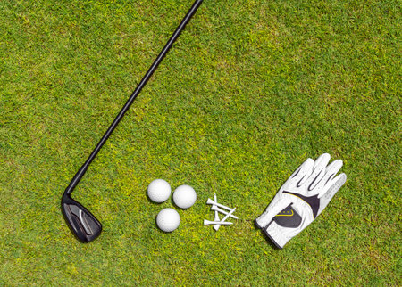 Top view of golf equipment on green grass on a golf course. Flat lay of golf club, balls, glove, teesの写真素材