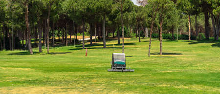 Golf course and a vehicle collecting golf balls. Ballpicker on driving range of golf clubの写真素材