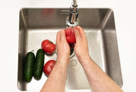 vegetables for salad are washed in cold water by mens handsの写真素材