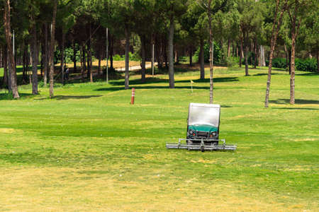 Golf course and golf cart collecting golf balls. Ballpicker on driving range of golf clubの写真素材