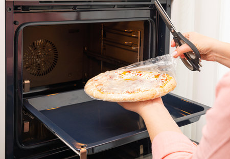Removing the packaging from the pizza before placing it in the ovenの写真素材