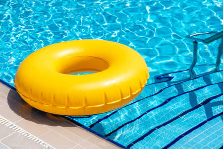 Yellow ring floating in blue swimming pool. Inflatable ring, rest conceptの写真素材