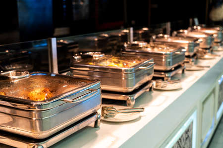 Catering buffet food with heated trays ready for service in hotel restaurantの写真素材