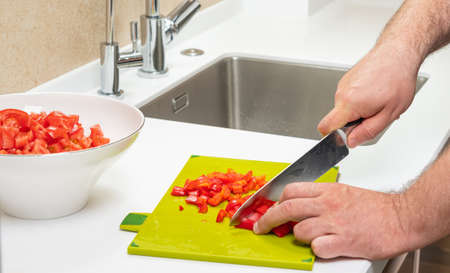 man preparing salad on cutting board beautiful view in modern kitchenの写真素材