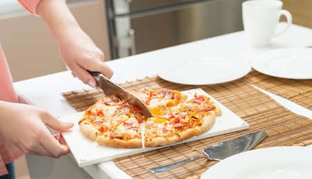 close-up homemade pizza being cut with a kitchen knifeの写真素材