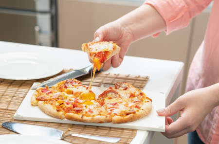 close-up a piece of homemade pizza served on a plate by female handsの写真素材