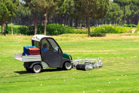 Golf course and a vehicle collecting golf balls. Ballpicker on driving range of golf clubの写真素材