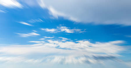 Panorama of blue sky with white clouds in clear weather with motion blur effectの写真素材