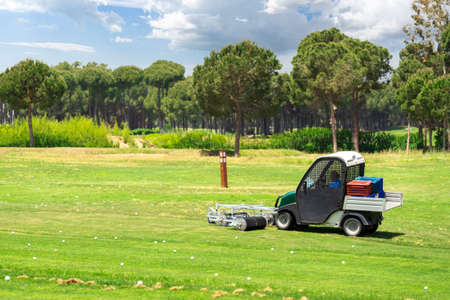Golf course and golf cart collecting golf balls. Ballpicker on driving range of golf clubの写真素材