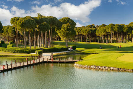 Golf course with lake, golf cart and playersの写真素材