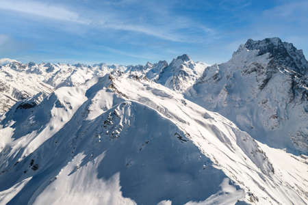 Snowy slope of mountains under clear skyの写真素材