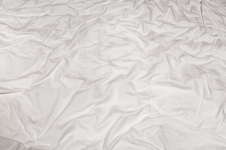 Close-up of the texture of a crumpled white sheet with tinted folded linesの写真素材