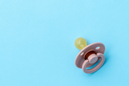 Pink baby pacifier on blue background with copy space, top view, flat lay. Newborn concept