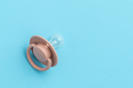 Pink baby pacifier on blue background with copy space, top view, flat lay. Newborn conceptの写真素材